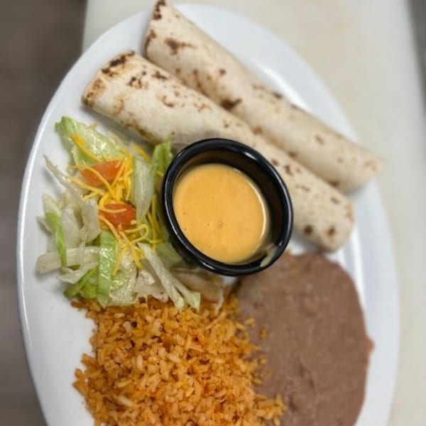 Two burritos, rice, refried beans, salad, and a side of cheese dip on a white plate.