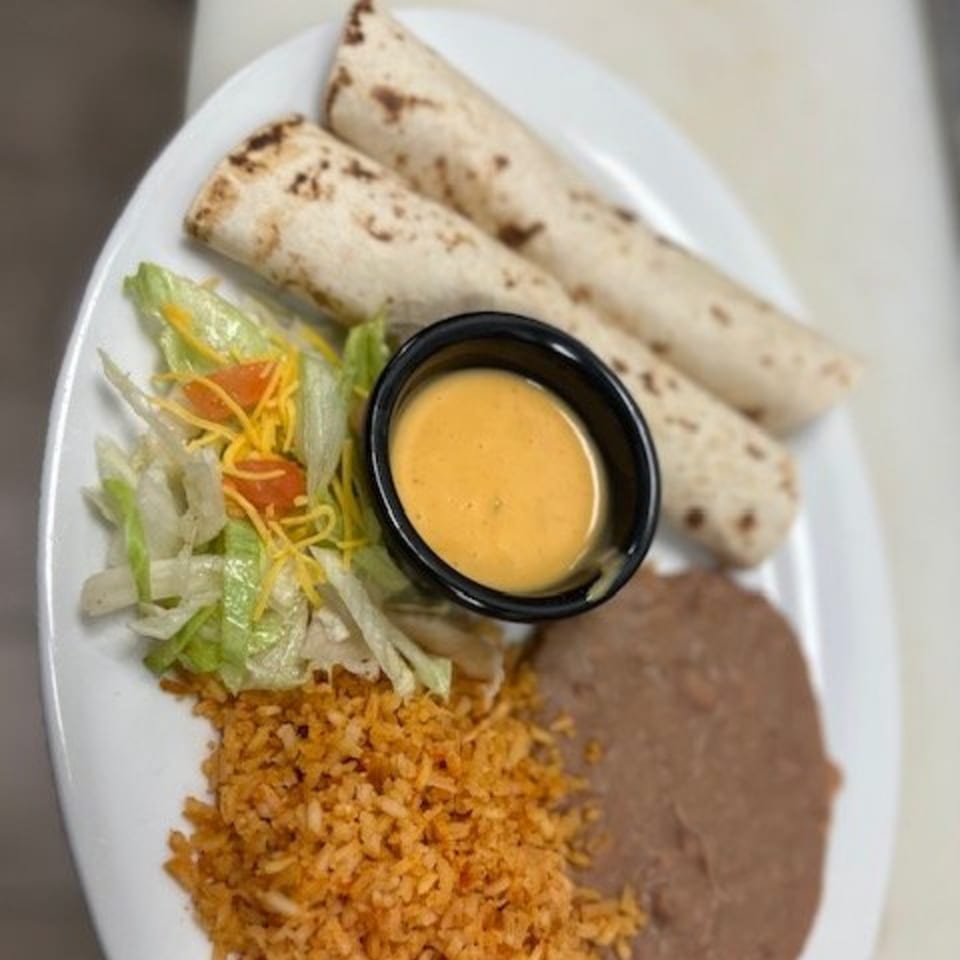 Two burritos, rice, refried beans, salad, and a side of cheese dip on a white plate.