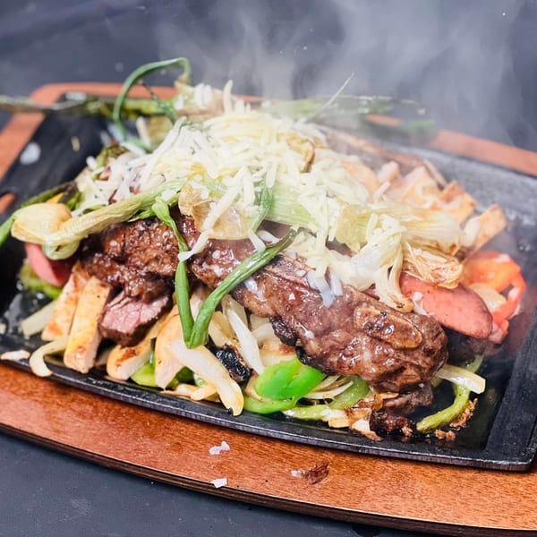 Sizzling Los Charros fajitas with steak, chicken, sausage, peppers, onions, and melted cheese.