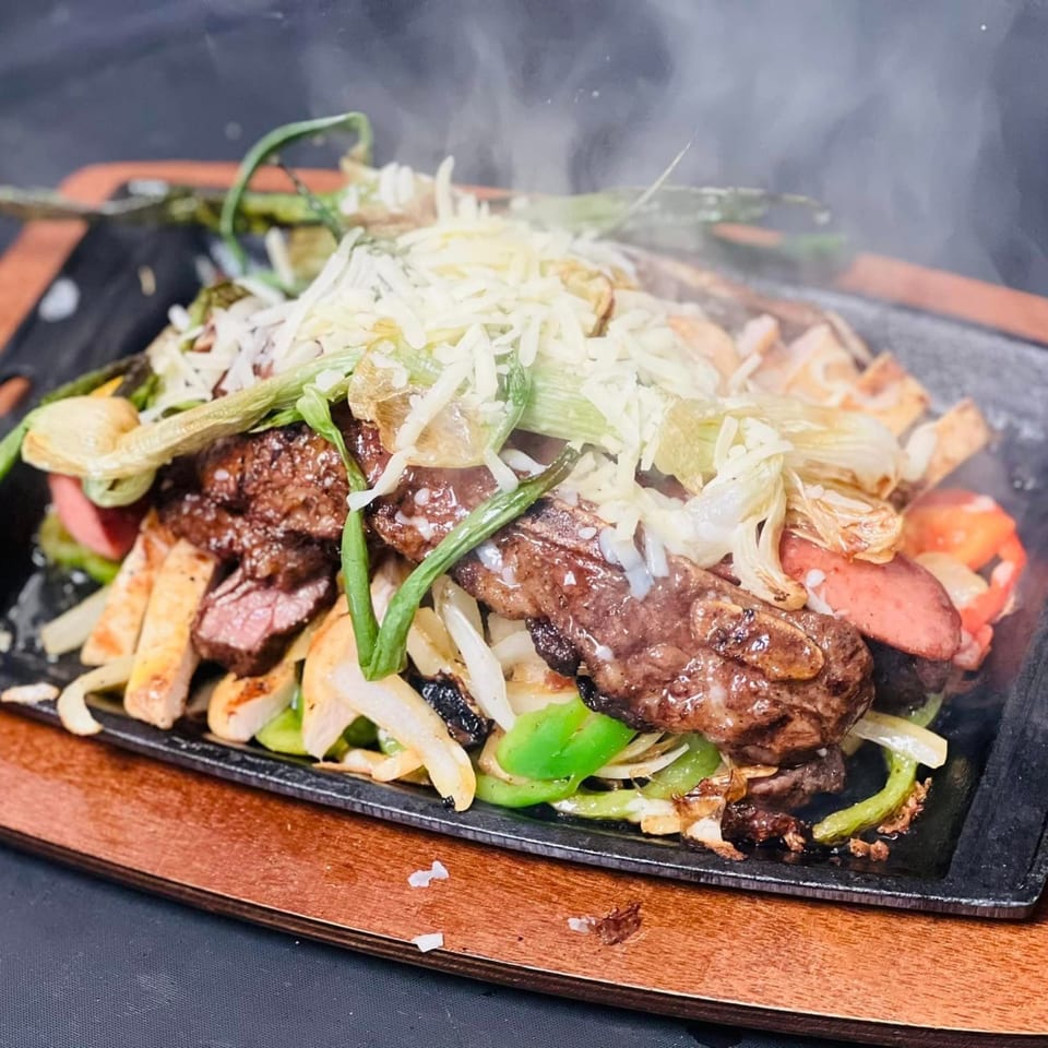 Sizzling Los Charros fajitas with steak, chicken, sausage, peppers, onions, and melted cheese.
