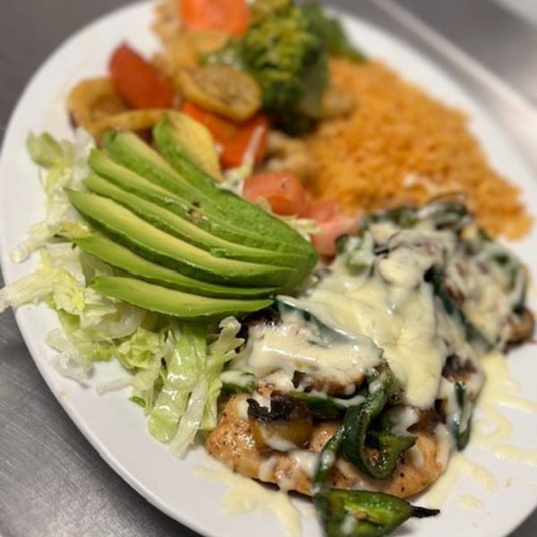 A Los Charros Mexican dish with cheesy chicken, avocado, lettuce, rice, and vegetables.