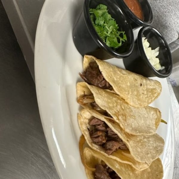 Four Los Charros Mexican street tacos with steak, onions, cilantro, salsa, and white onions.