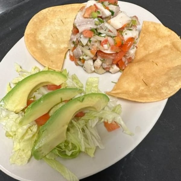 Los Charros' ceviche with diced fish, tomatoes, onions, cilantro, avocado slices, lettuce, and tostadas.