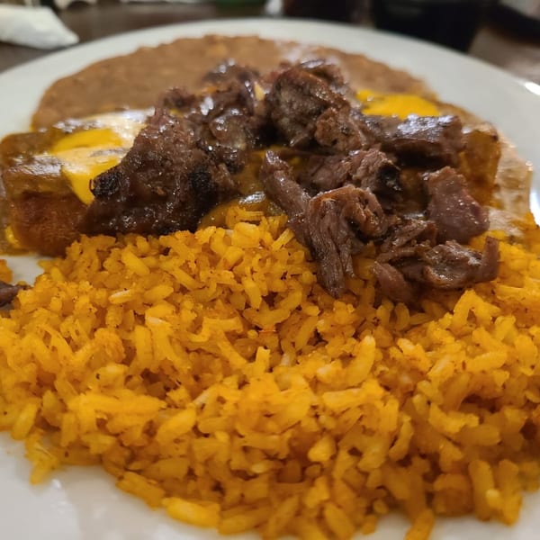 Close-up of a Los Charros Mexican dish with yellow rice, steak, and refried beans.