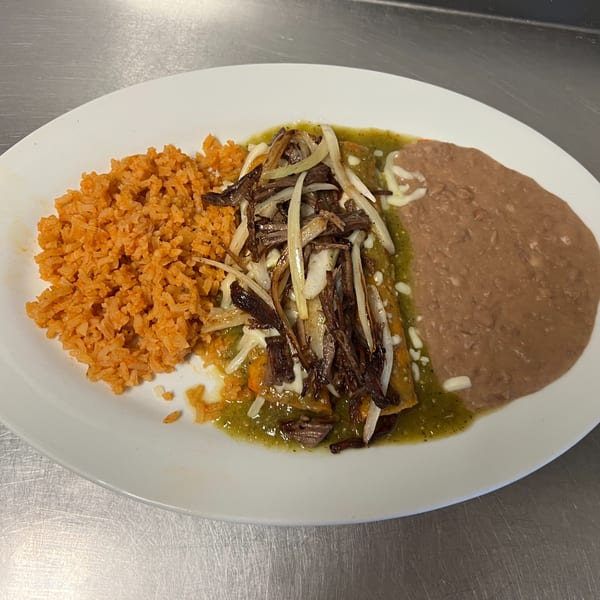 Los Charros' Mexican dish with orange rice, refried beans, and enchiladas topped with green sauce, meat, and onions.