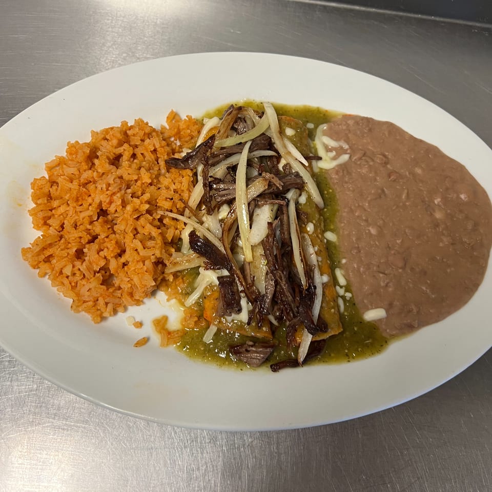 Los Charros' Mexican dish with orange rice, refried beans, and enchiladas topped with green sauce, meat, and onions.
