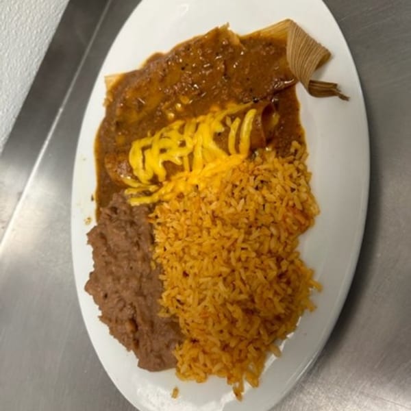 Los Charros' tamale and enchilada covered in sauce and cheese, served with rice and refried beans.