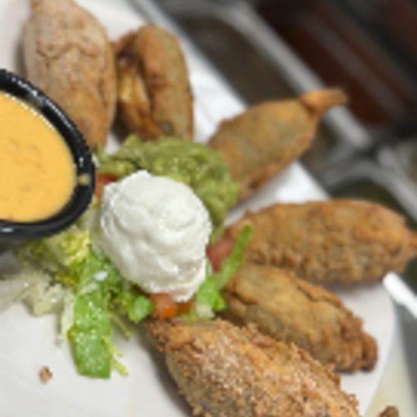 Los Charros' fried Mexican chiles rellenos with guacamole, sour cream, and a side of cheese dip.