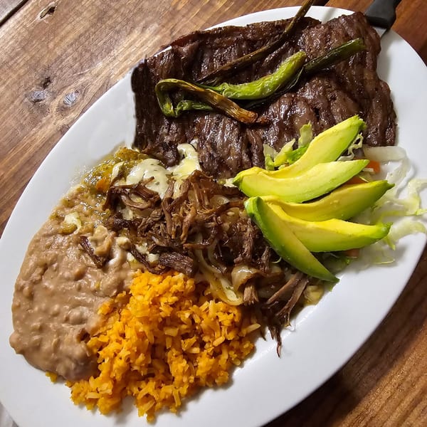 Los Charros' carne asada with refried beans, rice, shredded beef, avocado, and green chiles.