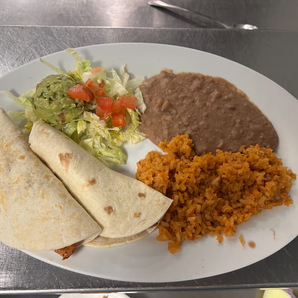 Two burritos with a side of guacamole, lettuce, tomatoes, refried beans, and Mexican rice.