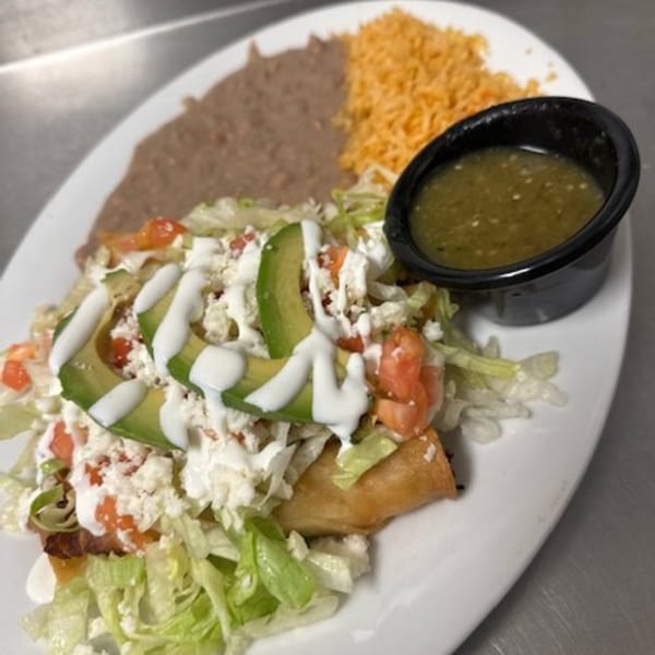 Los Charros Mexican dish with taquitos, refried beans, rice, salsa, and fresh toppings.