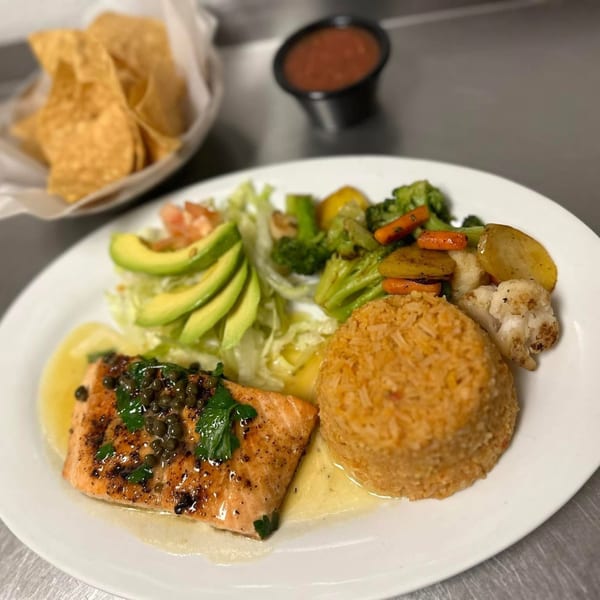 Los Charros' salmon with capers, rice, avocado, salad, and mixed vegetables, with chips and salsa.