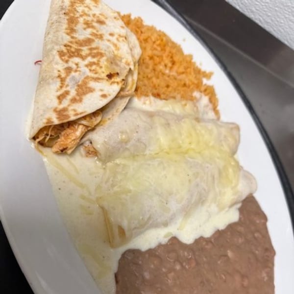 Los Charros' chicken quesadilla, cheesy enchiladas, rice, and refried beans on a white plate.